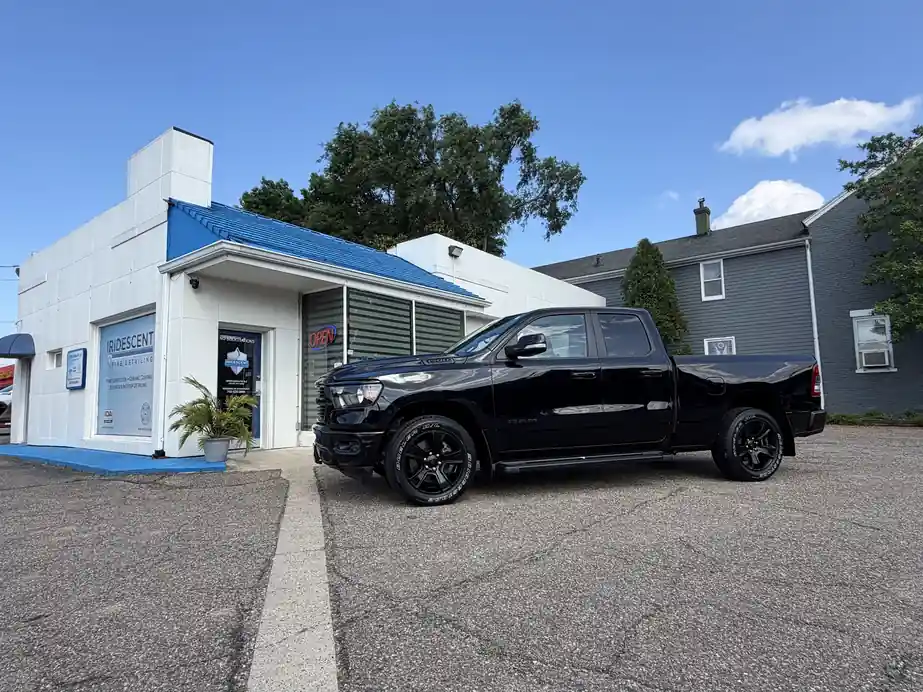 Black Ram 1500 parked in front of the white Iridescent Fine Detailing shop with the blue roof