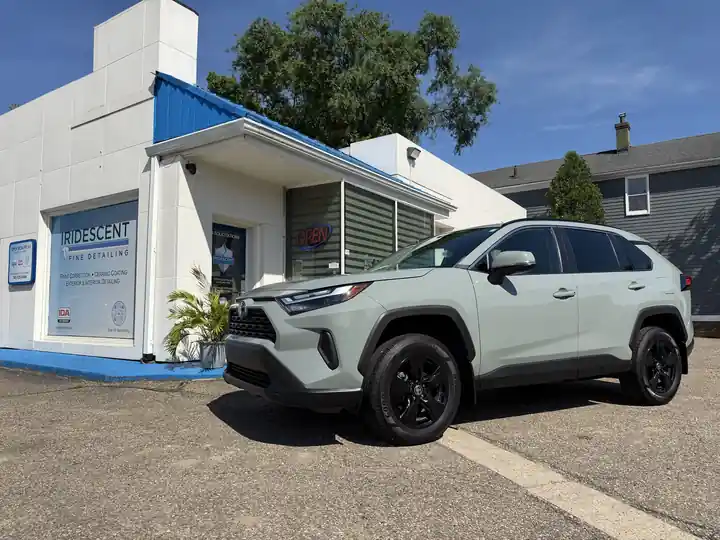Sage green Toyota RAV4 parked at the shop under a blue sky