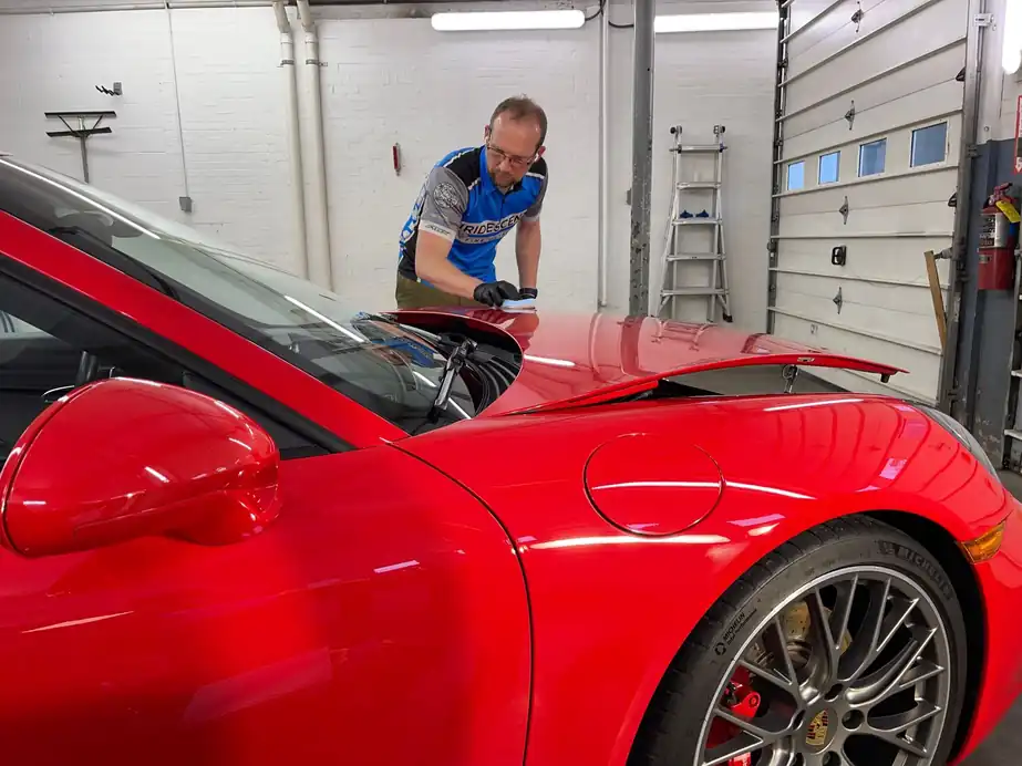 Hand polish on red Porsche paint in the bay