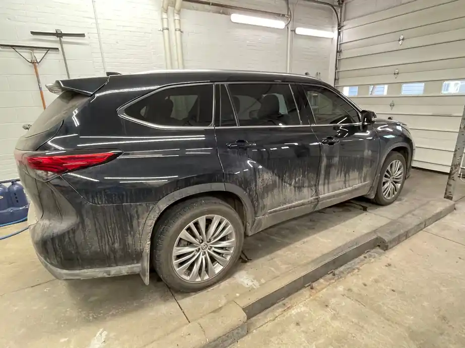 Black Highlander in the bay with road film streaked down the lower doors and rear quarter