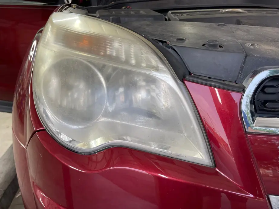 Hazed, yellowed headlight lens on a red SUV before restoration