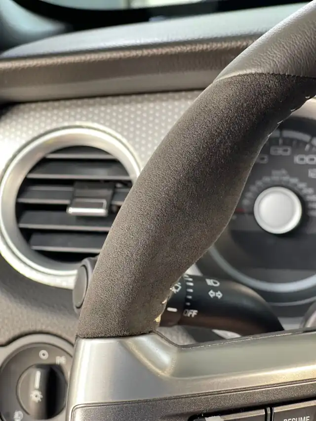 Same Alcantara steering wheel rim with an even, dark nap after the detail