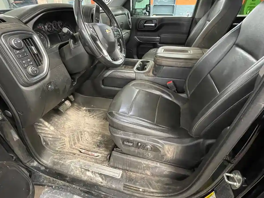 Silverado cab with dried dirt caked on the rubber floor mat and dust on the console and seat