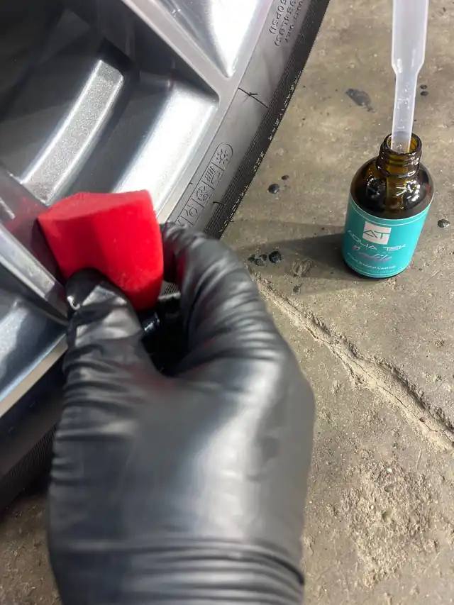 Gloved hand applying ceramic coating to a wheel face