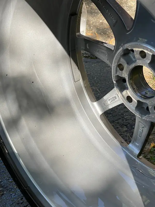 Prepped silver alloy wheel face with its spokes and hub in daylight